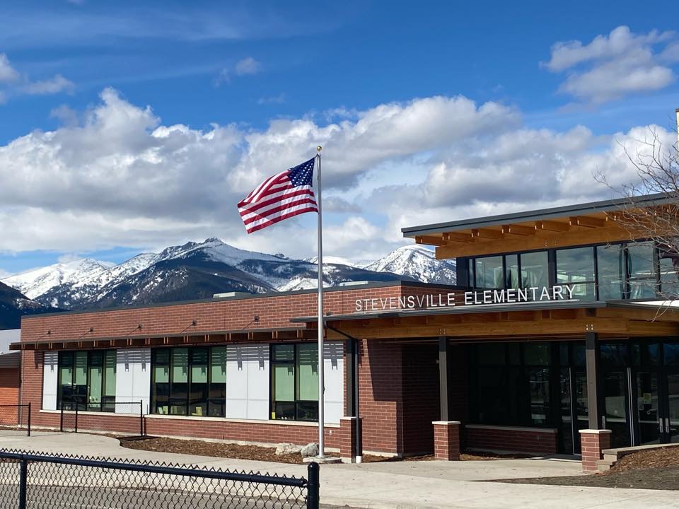 photo of the front of the primary school with the flag waving and blue sky in the background