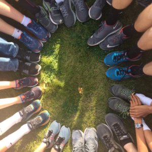 A photo of a circle of feet wearing running shoes of various colors