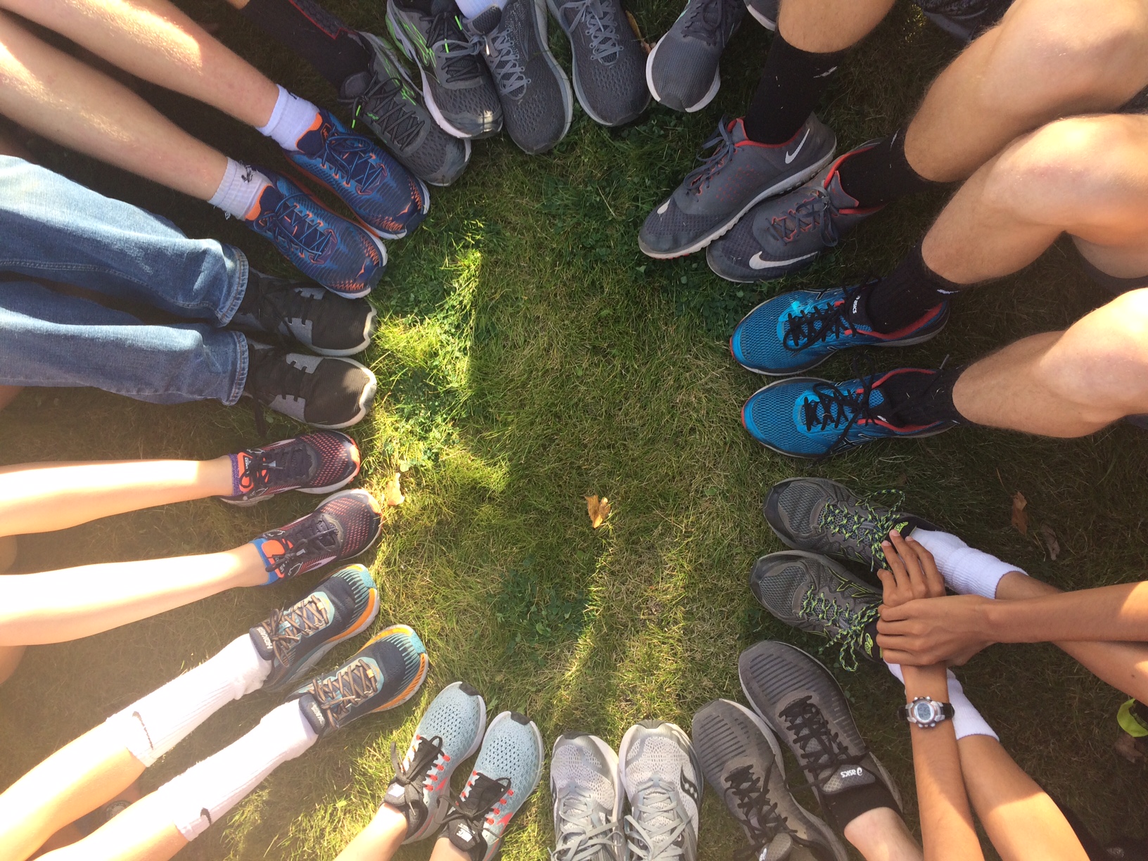 A photo of a circle of feet wearing running shoes of various colors