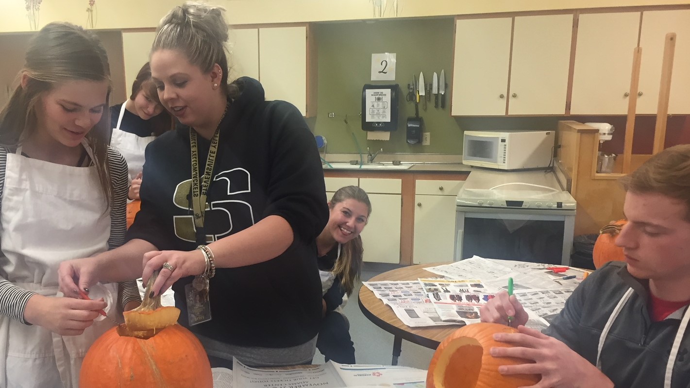 Photo of Amy Paxton - Family Consumer Science and FCCLA carving pumpkins with her students on national pumpkin day.