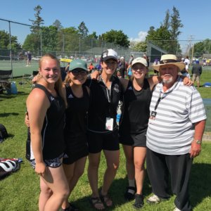 A Photo of the Tennis team with both coaches arm in arm shoulder to shoulder posing while standing on grass
