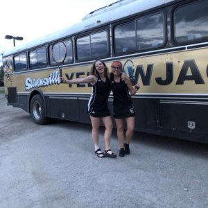 Erin and Jackie pose in front of the team bus.