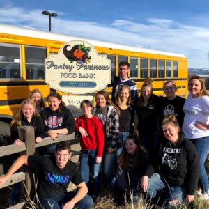 High School Student Council poses for a picture in front of a bus at the Stevensville Food Pantry