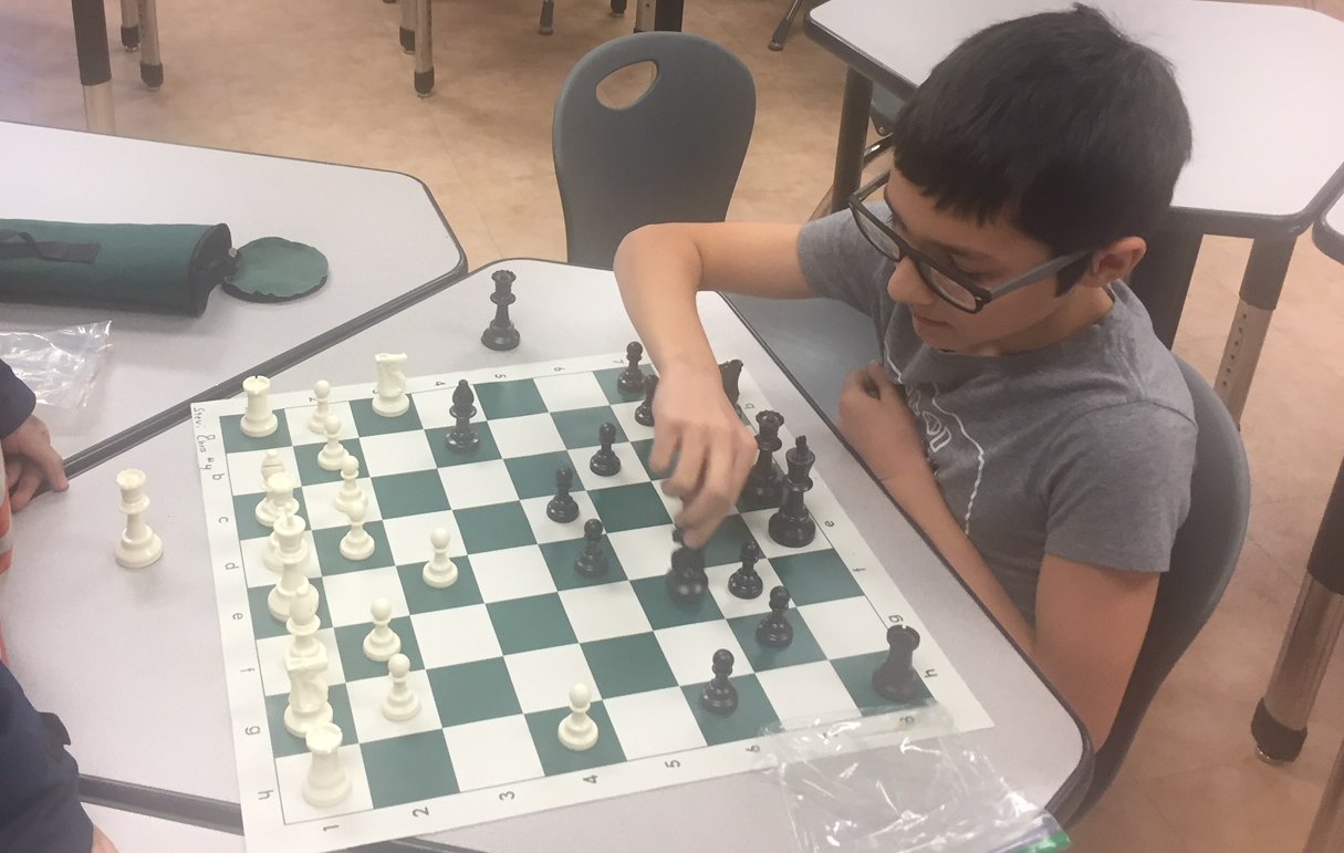 Photo of a member of Chess Club moving a piece