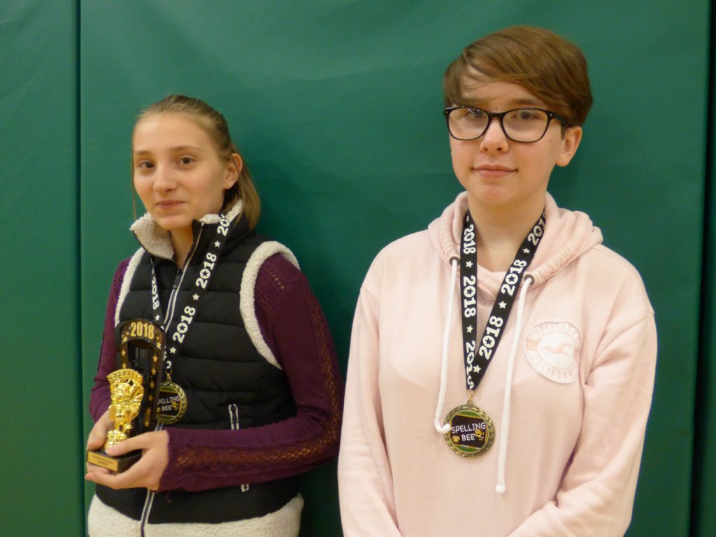 a photo of both the Spelling Bee Winner and Runner Up holding their trophies and wearing their medals