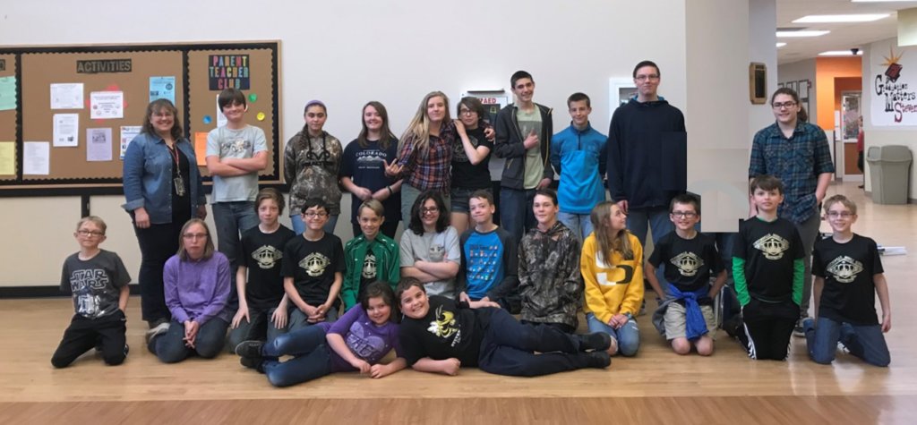 A photo of the entire chess club with students standing, kneeling or laying on the floor smiling for the picture