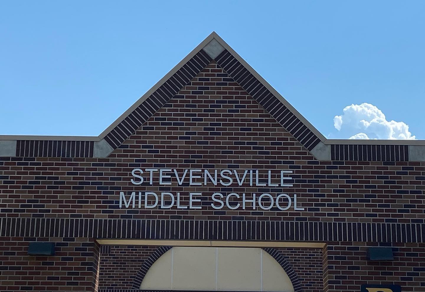 photo of the front entrance of the stevensville middle school with the words in silver letters on red brick