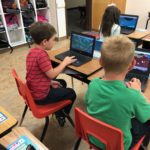 Two boys use their new chromebooks at a table