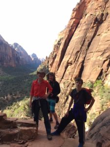 A photo of nurse Connie hiking with her two sons in Zion National Park standing in a canyon posing for a photo.