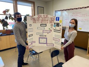 fenn chimo and olivia peretto stand on either side of their exhibit board